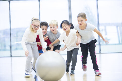 Fröhliche Schüler haben Spaß mit dem Gymnastikball während des Sportunterrichts - WESTF24100