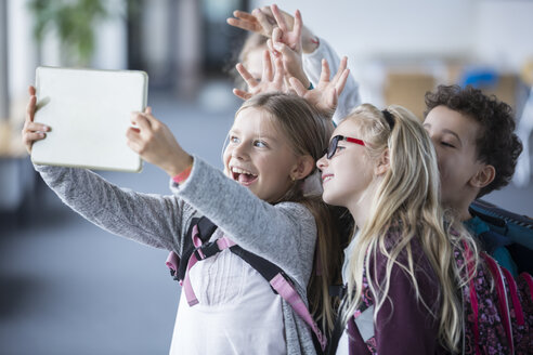 Fröhliche Schüler, die einen Moment mit einem Tablet in ihrem Klassenzimmer festhalten - WESTF24103