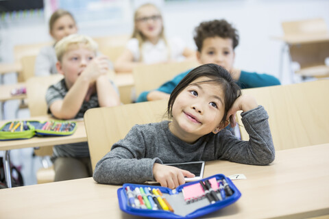 Eine Schülerin posiert mit ihren Mitschülern in einem Klassenzimmer., lizenzfreies Stockfoto