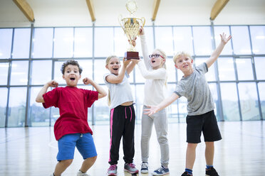 Ecstatic students proudly displaying their trophy in the school gymnasium - WESTF24114