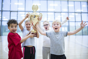 Excited students proudly display their trophy after winning a sports competition in the school gym. - WESTF24118
