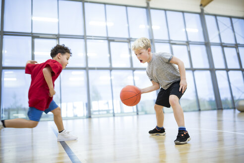 Zwei junge Schüler genießen ein Basketballspiel während des Sportunterrichts in der Turnhalle der Schule - WESTF24129