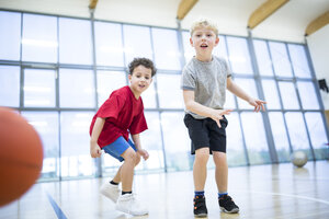 Zwei begeisterte Schüler, die während des Sportunterrichts in der Schulsporthalle ihre Basketballkünste verbessern - WESTF24130