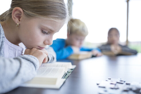 A diligent schoolgirl engrossed in reading during her break in the school's cozy break room - WESTF24142