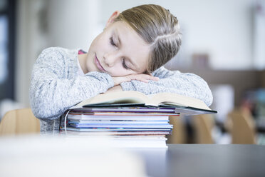 Ein Schüler mit Schlafmangel findet während eines langen Schultages Trost in einem behelfsmäßigen Bett aus Büchern - WESTF24147