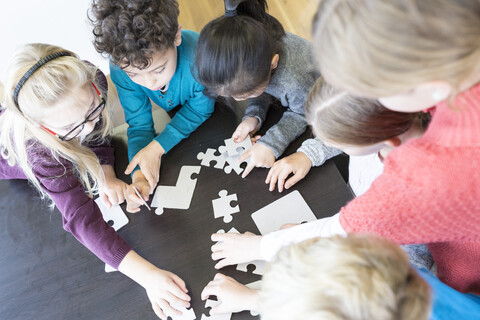 Schüler arbeiten im Unterricht gemeinsam an einem Puzzle, lizenzfreies Stockfoto