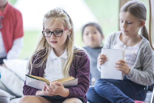 Mädchen, die während der Schulpause im gemütlichen Pausenraum in eine Lektüre vertieft sind - WESTF24153