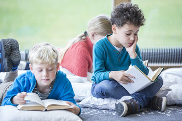 Students engrossed in reading books while seated on the floor of the school's break room - WESTF24154