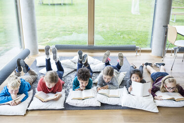 Schüler, die sich in der Pause im Lesesaal mit Büchern auf dem Boden ausruhen - WESTF24157