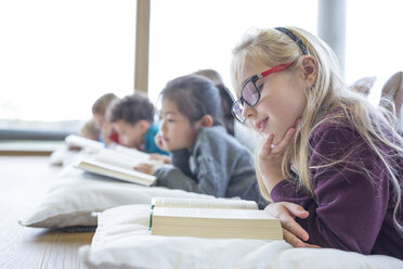 Students relaxing on the floor with books during their school break in the common area - WESTF24159