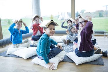 Fröhliche Schülerinnen und Schüler machen eine Pause im Aufenthaltsraum der Schule und stellen ihre Gleichgewichtsfähigkeiten mit Büchern auf dem Kopf unter Beweis - WESTF24163