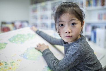 Smart and studious schoolgirl engrossed in her book while sitting in a classroom - WESTF24166