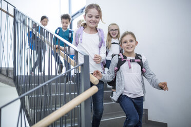 Fröhliche Schüler verabschieden sich, während sie mit einem Lächeln im Gesicht die Schultreppe hinuntergehen - WESTF24170
