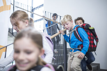 Fröhliche Schüler verabschieden sich auf der Schultreppe und freuen sich auf das Ende des Tages und die bevorstehenden Abenteuer - WESTF24171
