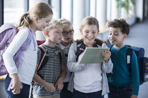 Aufgeregte Schülerinnen und Schüler versammeln sich im Schulflur um ein Tablet und sind begierig darauf, zu lernen und neue Technologien zu erkunden - WESTF24189