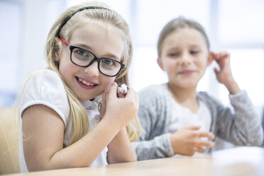 Zufriedener Schüler im Klassenzimmer hält beim Lernen selbstbewusst die Computermaus - WESTF24201