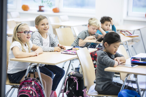 Schüler sitzen aufmerksam an ihren Tischen in einem Klassenzimmer und sind bereit, zu lernen und sich an Bildungsaktivitäten zu beteiligen, lizenzfreies Stockfoto