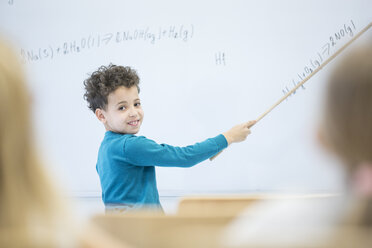 Ein Schüler erklärt seinen Mitschülern im Unterricht selbstbewusst eine mathematische Formel auf der Tafel - WESTF24210