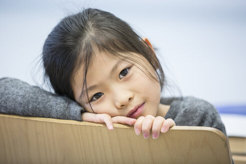 Ein junger Schüler sitzt auf einem Stuhl in einem Klassenzimmer und sieht konzentriert und lernbereit aus. - WESTF24212