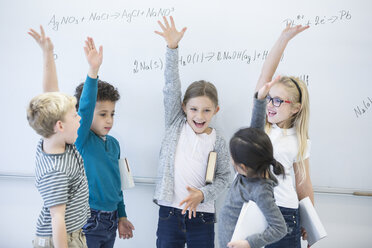 Begeisterte Schülerinnen und Schüler nehmen eifrig an einer Mathematikstunde teil und heben eifrig die Hände, um Gleichungen an der Tafel zu lösen - WESTF24216