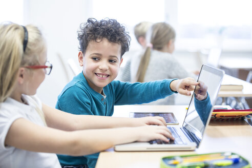 Gemeinsames Lernen in Aktion: Ein Junge und ein Mädchen arbeiten im Unterricht gemeinsam an einem Laptop - WESTF24224