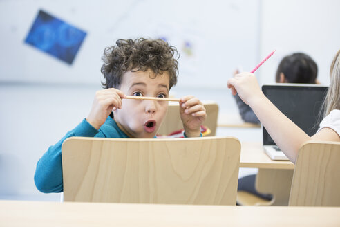 Ein Schüler im Klassenzimmer starrt gedankenverloren auf seinen Bleistift und überlegt, was er als nächstes tun könnte - WESTF24226