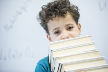 Ein schick gekleideter Schüler trägt selbstbewusst seine Bücher, bereit für einen Tag voller Lernen im Klassenzimmer - WESTF24229