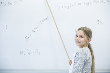 Begeisterte Schülerin demonstriert selbstbewusst und mit einem Lächeln eine mathematische Gleichung an der Tafel im Klassenzimmer - WESTF24232