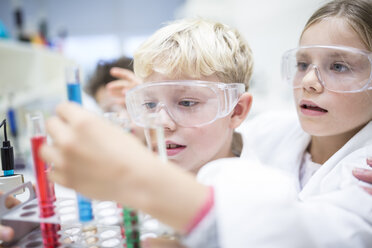 Schülerinnen und Schüler führen im naturwissenschaftlichen Unterricht Experimente mit verschiedenen Flüssigkeiten in Reagenzgläsern durch - WESTF24239