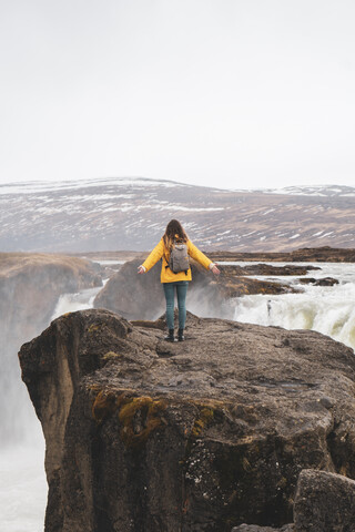 Island, Frau steht am Godafoss-Wasserfall, lizenzfreies Stockfoto