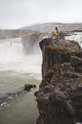 Iceland, woman standing at Godafoss waterfall - KKAF01040