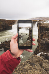 Island, Hand hält Handy mit Bild des Godafoss-Wasserfalls - KKAF01044