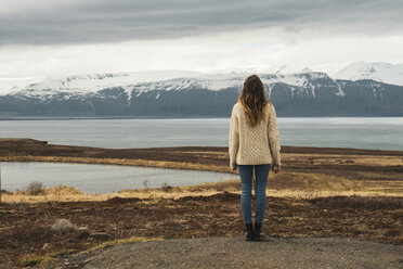 Iceland, woman standing at lakeside - KKAF01058