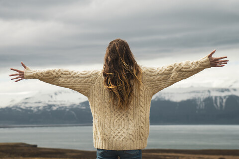 Iceland, woman standing at lakeside with outstretched arms stock photo