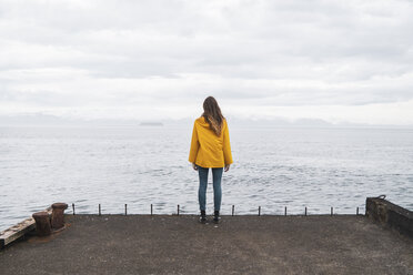 Iceland, woman standing at the sea - KKAF01063