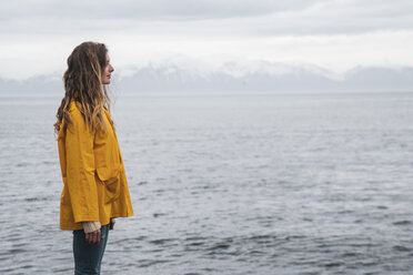 Iceland, woman standing at the sea - KKAF01065