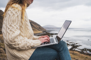 Island, Frau mit Laptop an der Küste - KKAF01072