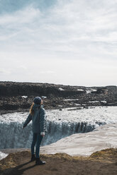Iceland, woman standing at Dettifoss waterfall - KKAF01082