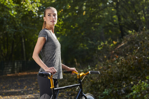 Portrait of sportive young woman with bicycle in a forest stock photo