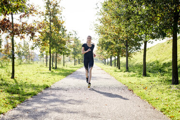 Junge Frau läuft in einem Park - MMIF00088