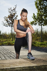 Sportive young woman stretching her leg - MMIF00093