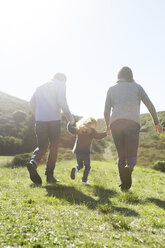 Rear view of mid adult couple and daughter strolling in field - ISF05789