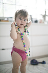 Porträt eines weiblichen Kleinkindes, das in der Küche eine Perlenkette anprobiert - ISF05792