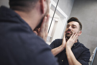 Mirror image of bearded man with hands on face - ISF05809