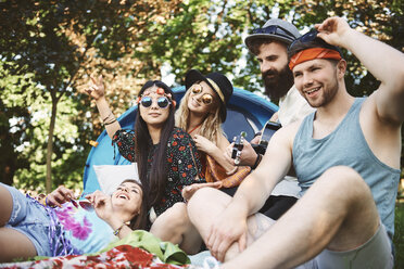 Five young adult friends playing acoustic guitar while festival camping - ISF05819