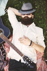 Draufsicht auf einen jungen männlichen Hipster auf dem Rücken liegend auf einem Festival - ISF05826