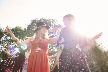 Zwei junge Boho-Frauen tanzen im Sonnenlicht auf einem Festival - ISF05829