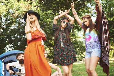 Three young boho women dancing together at festival - ISF05830