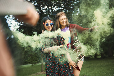 Junge Boho-Frauen tanzen mit grünen Rauchfackeln auf einem Festival - ISF05833