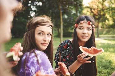 Junge Boho-Frauen essen Melonenscheiben auf einem Festival - ISF05838